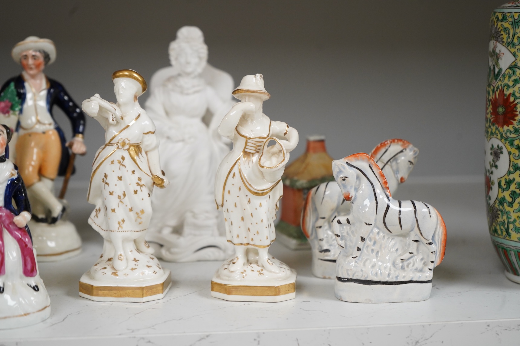 A group of mid-19th century Staffordshire porcelain figures, two models of zebras and a early 19th century Derby biscuit porcelain figure of a seated lady, largest 18cm high